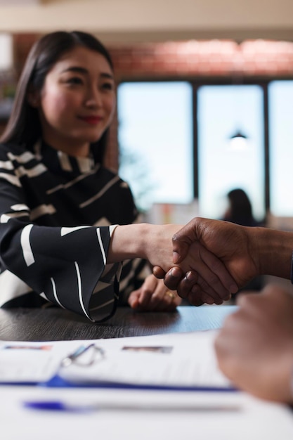 Aziatische recruiter die de ondernemer de hand schudt tijdens een interviewvergadering in het startbedrijfskantoor. Zakenman die cv-cv bespreekt voordat hij een vrouw rekruteert voor een hr-baan. Inhuur concept