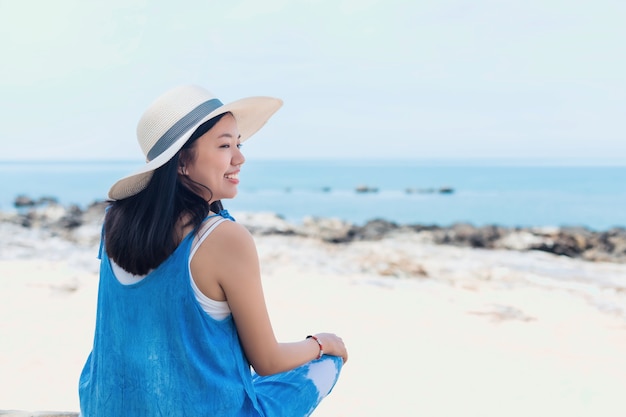 Aziatische reiziger vrouw zitten en ontspannen op het strand door de zee-achtergrond. Concept van gelukkig reizen op vakantie weekend.