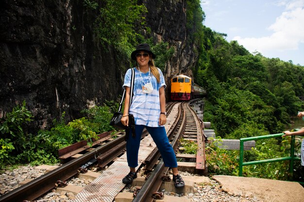 Foto aziatische reizigers thaise vrouwen reizen bezoek en poseren portret op spoortrein om foto te nemen en landschap kwai rivier te bekijken in sai yok waterfall national park in de tham krasae-grot in kanchanaburi, thailand