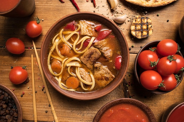 Aziatische rundvleessoep traditionele Oezbeekse schotel is Lagman Turkse pizza knoflook tomaten noedels rode peper ui voedsel plat lag bovenaanzicht houten rustieke achtergrond close-up