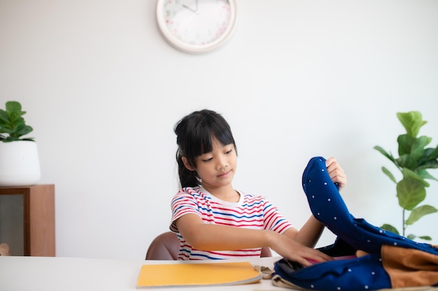 Aziatische schattige basisschoolmeisjes die hun schooltassen inpakken en zich voorbereiden op de eerste schooldag de ochtendschoolroutine voor de dag in het leven maakt zich klaar