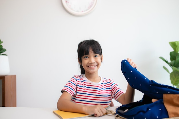 Aziatische schattige basisschoolmeisjes die hun schooltassen inpakken en zich voorbereiden op de eerste schooldag De ochtendschoolroutine voor de dag in het leven maakt zich klaar