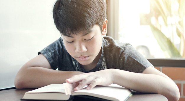 Aziatische schattige jongen lezen boeken in het café.