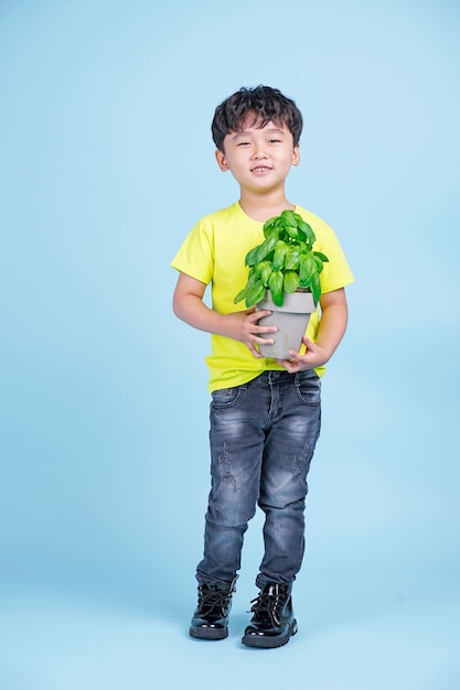 Aziatische schattige kleine knappe jongen houdt een pot met groene plant en glimlach, milieuvriendelijk concept