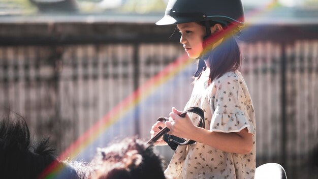 Aziatische schoolmeisje met paardrijden of oefenen van paardenrijden op een paardenboerderij