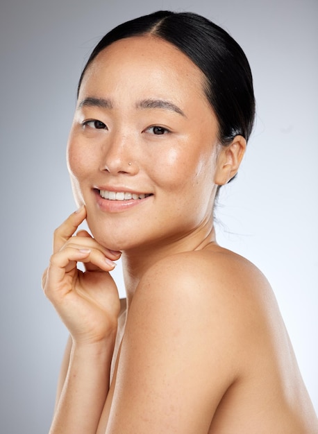 Aziatische schoonheid en huidverzorging met portret van vrouw voor gezichtswellness en cosmetica Glimlach gezondheid en luxe met meisje in grijze achtergrondstudio voor natuurlijke make-up spa en model gezichtsproduct