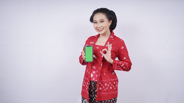 Aziatische schoonheid in kebaya weergegeven: smartphone scherm gebaar ok geïsoleerd op witte achtergrond