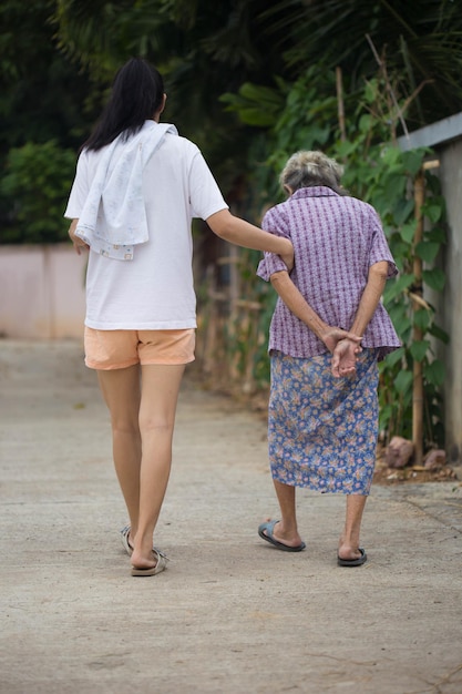 Aziatische senior moeder en volwassen dochter hand in hand wandelen in het buitenpark