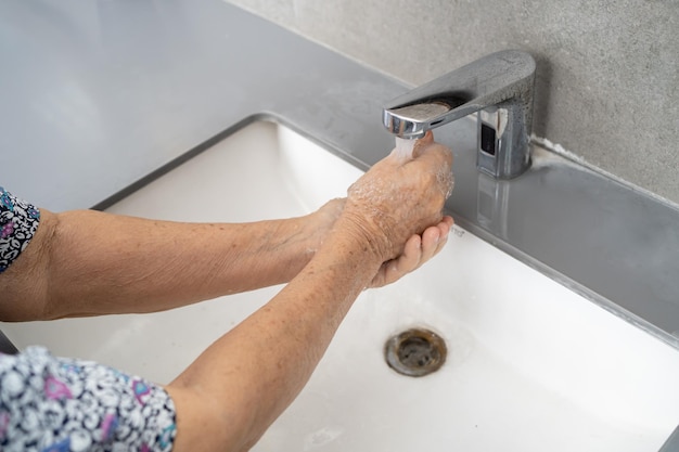 Aziatische senior of bejaarde oude dame vrouw patiënt hand wassen met zeep en schoon water om veiligheidsinfectie te beschermen en Novel Coronavirus Covid19 virus bacteriën en ziektekiemen te doden