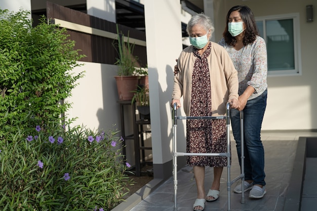 Aziatische senior of oudere oude dame vrouw loopt met rollator en draagt een gezichtsmasker ter bescherming van de veiligheidsinfectie Covid-19 Coronavirus.