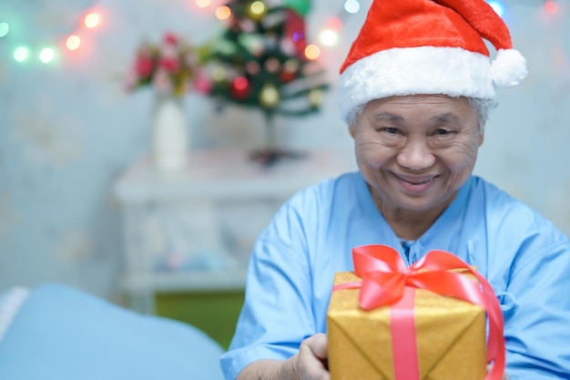 Aziatische senior of oudere oude dame vrouw patiënt met kerstman helper hoed met geschenkdoos in Kerstmis en Nieuwjaar viering festival vakantie feest in het ziekenhuis.