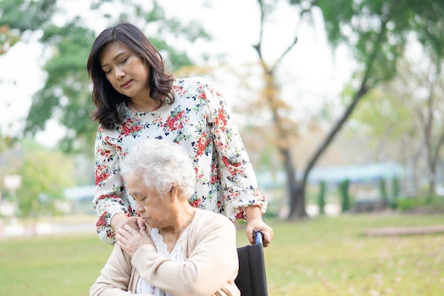 Aziatische senior of oudere oude dame vrouw patiënt met zorg, hulp en ondersteuning door verzorger op rolstoel in park in vakantie, gezond sterk medisch concept.