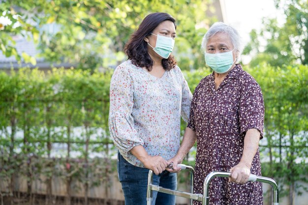 Aziatische senior vrouw loopt met rollator en draagt een gezichtsmasker om het coronavirus te beschermen