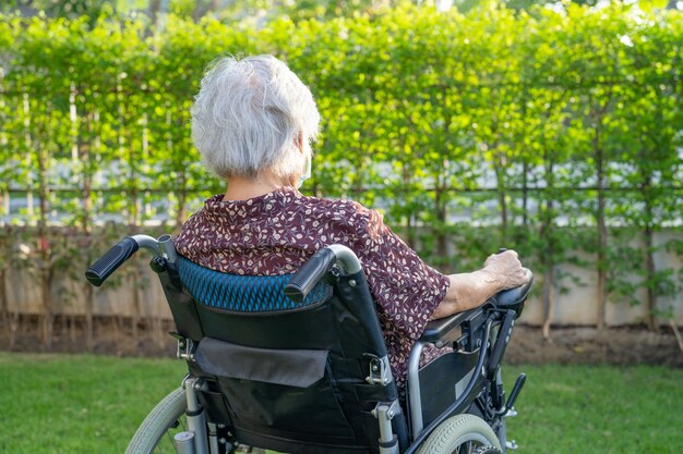 Aziatische senior vrouw patiënt op elektronische rolstoel in park.