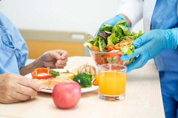 Aziatische senior vrouw patiënt zalm steak ontbijt eten met plantaardig gezond voedsel