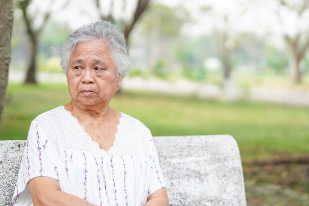 Aziatische senior vrouw zittend op stoel in park met hoop