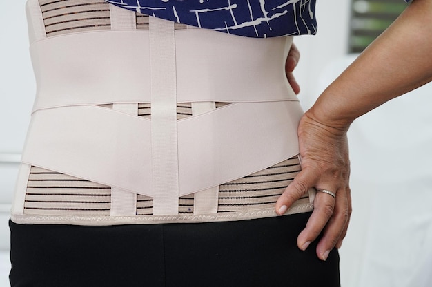 Aziatische senioren die een elastische steungordel dragen, kunnen helpen bij het verminderen van rugpijn.