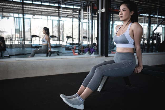 Aziatische slanke vrouw speelt triceps in de sportschool