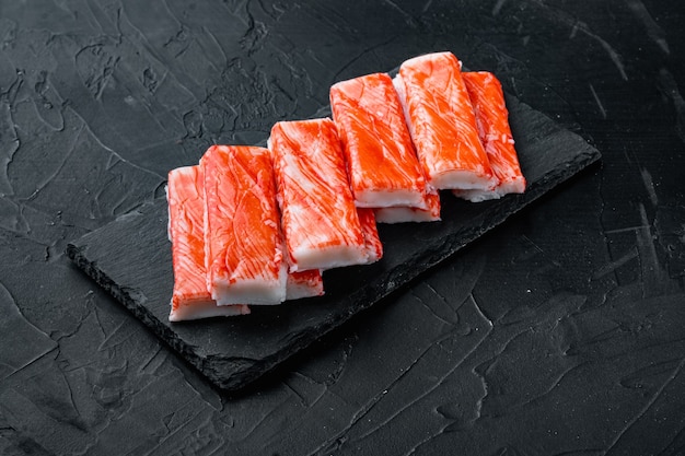 Aziatische snack surimi set, op stenen bord, op zwarte achtergrond