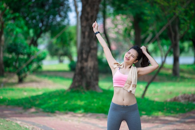 Aziatische sportieve vrouw die haar armen uitstrekt en frisse lucht ademt in het parkThailand mensen oefenen concept