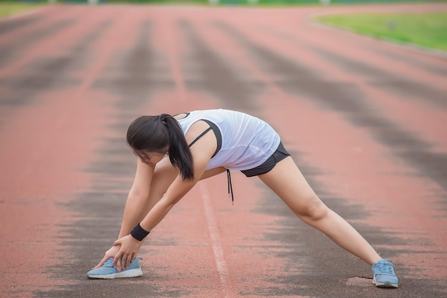 Aziatische sportieve vrouw die het lichaam uitrekt en frisse lucht ademt in het park Thailand mensenFitness en oefeningsconcept Joggen in de baan