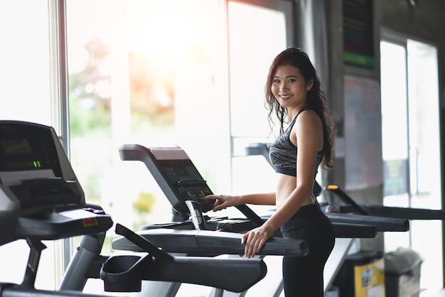 Aziatische sportvrouw die op loopband in fitnessclub loopt Cardiotraining Gezonde levensstijl kerel die in gymnastiek opleidt Sport lopend concept