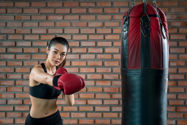 Aziatische sportvrouw draagt bokshandschoen in de sportschoolThailand-mensentraining