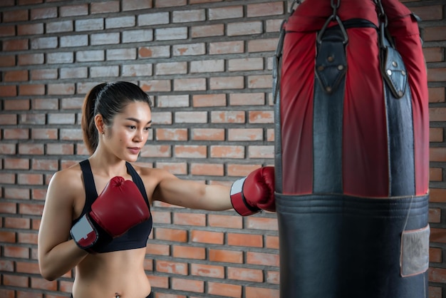 Aziatische sportvrouw draagt bokshandschoen in de sportschoolThailand-mensentraining