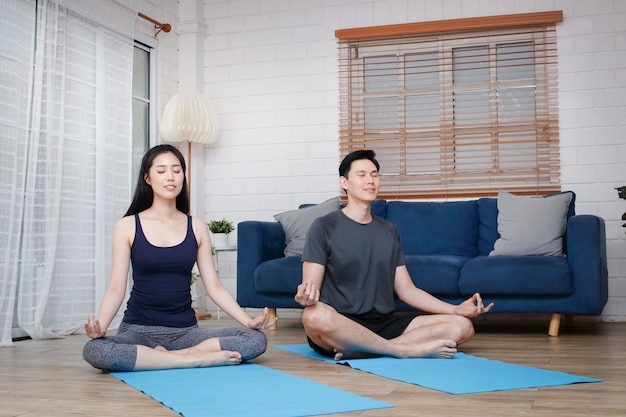 Aziatische stellen doen thuis samen yoga-oefeningen tijdens COVID-19 en sociale afstand nemen. Concept om gezond te houden. kopieer ruimte