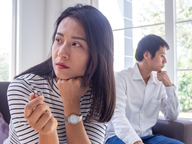 Aziatische stellen hebben conflicten. de vrouw doet de trouwring af achter een gestreste echtgenoot en familieproblemen.