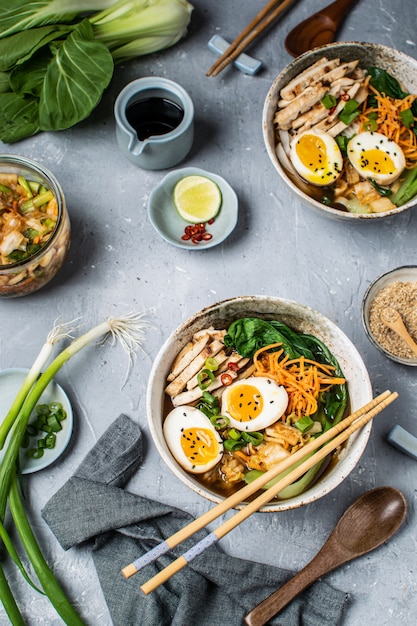 Aziatische stijl ramen noedelsoep met bok choy, wortel, limoen, sesamzaadjes, kip en ei