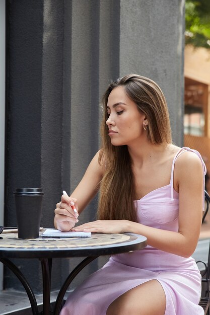 Aziatische student meisje met kopje koffie buiten café studeren huiswerk maken