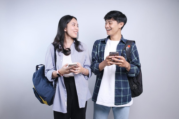 Aziatische studenten dragen rugzak en casual kleding praten terwijl ze smartphones vasthouden