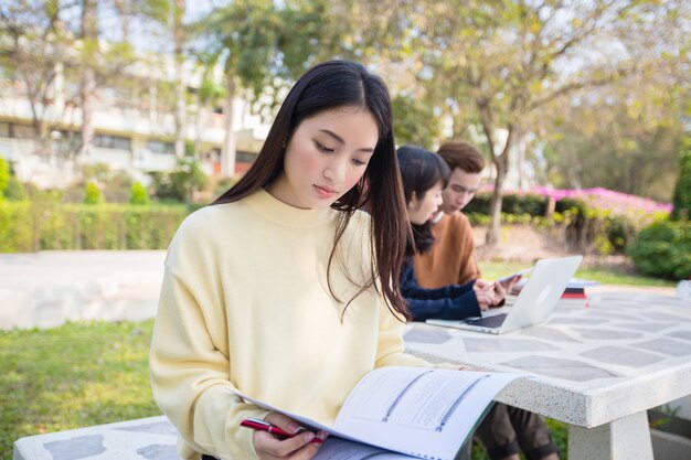 Aziatische studenten gebruiken notebooks en tablets om thuis in de tuin te werken en te studeren tijdens de coronavirusepidemie en quarantaine thuis