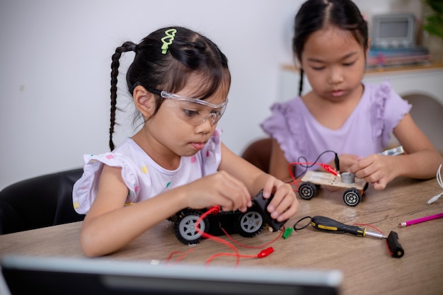 Aziatische studenten leren thuis door robotwagens en elektronische boordkabels te coderen in STEM STEAM wiskunde techniek wetenschap technologie computercode in robotica voor kinderen concepten