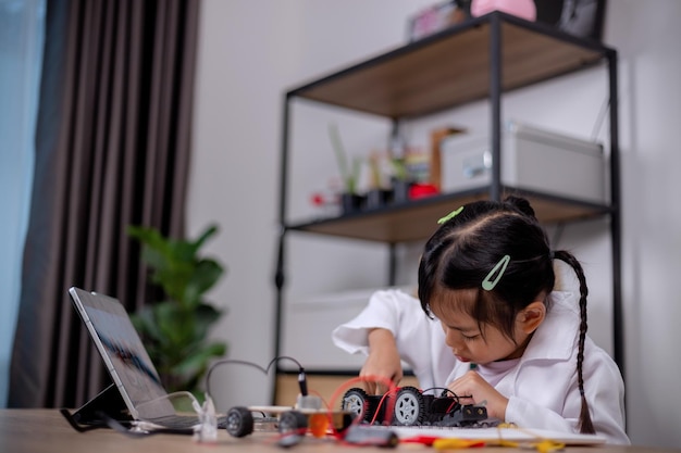 Aziatische studenten leren thuis door robotwagens en elektronische boordkabels te coderen in STEM STEAM wiskunde techniek wetenschap technologie computercode in robotica voor kinderen concepten