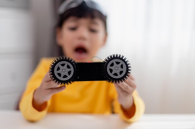 Aziatische studenten leren thuis in het coderen van robot auto's en elektronische boord kabels in STEM STEAM wiskunde techniek wetenschap technologie computer code in robotica voor kinderen concept