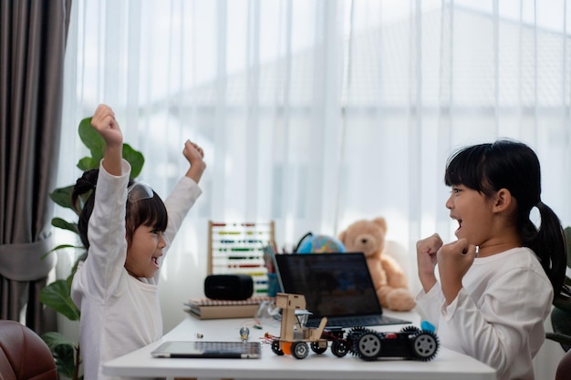 Aziatische studenten leren thuis in het coderen van robot auto's en elektronische boord kabels in STEM STEAM wiskunde techniek wetenschap technologie computer code in robotica voor kinderen concept
