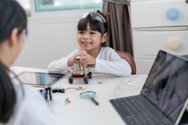 Aziatische studenten leren thuis in het coderen van robot auto's en elektronische boord kabels in STEM STEAM wiskunde techniek wetenschap technologie computer code in robotica voor kinderen concept