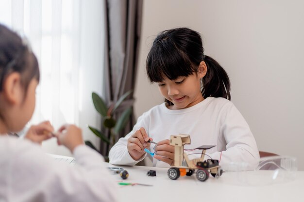 Aziatische studenten leren thuis in het coderen van robot auto's en elektronische boord kabels in STEM STEAM wiskunde techniek wetenschap technologie computer code in robotica voor kinderen concept
