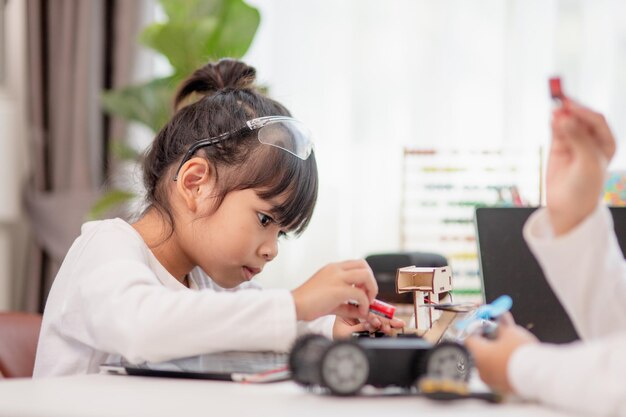 Aziatische studenten leren thuis in het coderen van robot auto's en elektronische boord kabels in STEM STEAM wiskunde techniek wetenschap technologie computer code in robotica voor kinderen concept