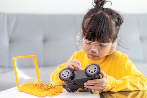 Aziatische studenten leren thuis in het coderen van robotauto's en elektronische bordkabels in STEM, STEAM, wiskunde engineering science technology computercode in robotics for kids concept.