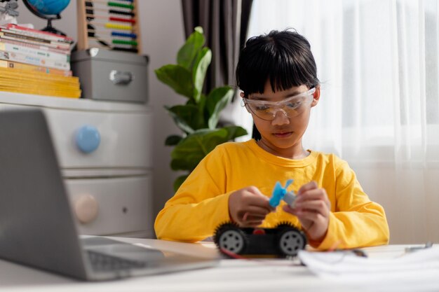 Aziatische studenten leren thuis in het coderen van robotauto's en elektronische bordkabels in STEM STEAM wiskunde engineering wetenschap technologie computercode in robotica voor kinderen concept