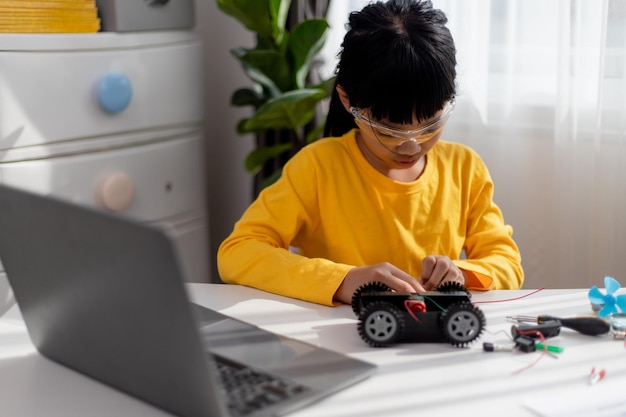 Aziatische studenten leren thuis in het coderen van robotauto's en elektronische bordkabels in STEM STEAM wiskunde engineering wetenschap technologie computercode in robotica voor kinderen concept