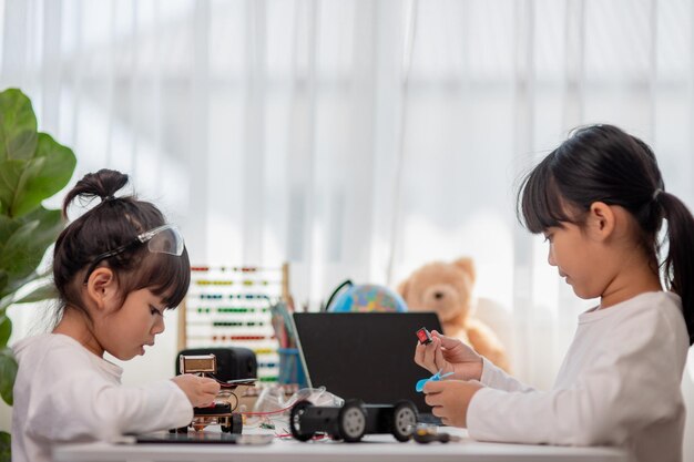 Aziatische studenten leren thuis in het coderen van robotauto's en elektronische bordkabels in STEM STEAM wiskunde engineering wetenschap technologie computercode in robotica voor kinderen concept