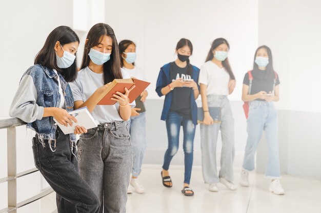 Aziatische studenten terug naar school met beschermend gezichtsmasker die op de campus studeren