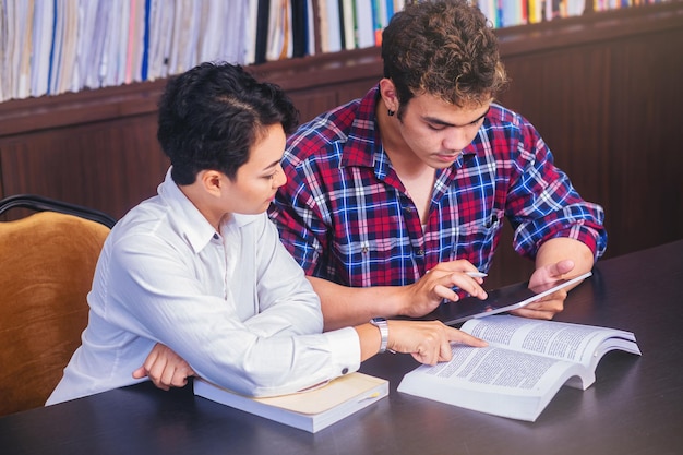 Aziatische studenten zitten lezen, studeren, onderzoeken, tutorboeken met vrienden.