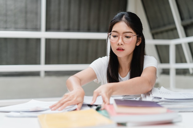 Aziatische studentenvrouwen die boeken lezen in bibliotheek aan de universiteit