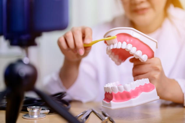 Aziatische tandartsvrouw die online thuis werkt Blogvideo opnemen voor instructiehandleiding tanden poetsen. Tandheelkunde en tanden gezondheidszorg.