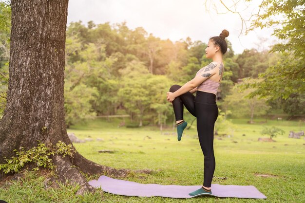 Aziatische tattoo jonge vrouw doet yoga in het park